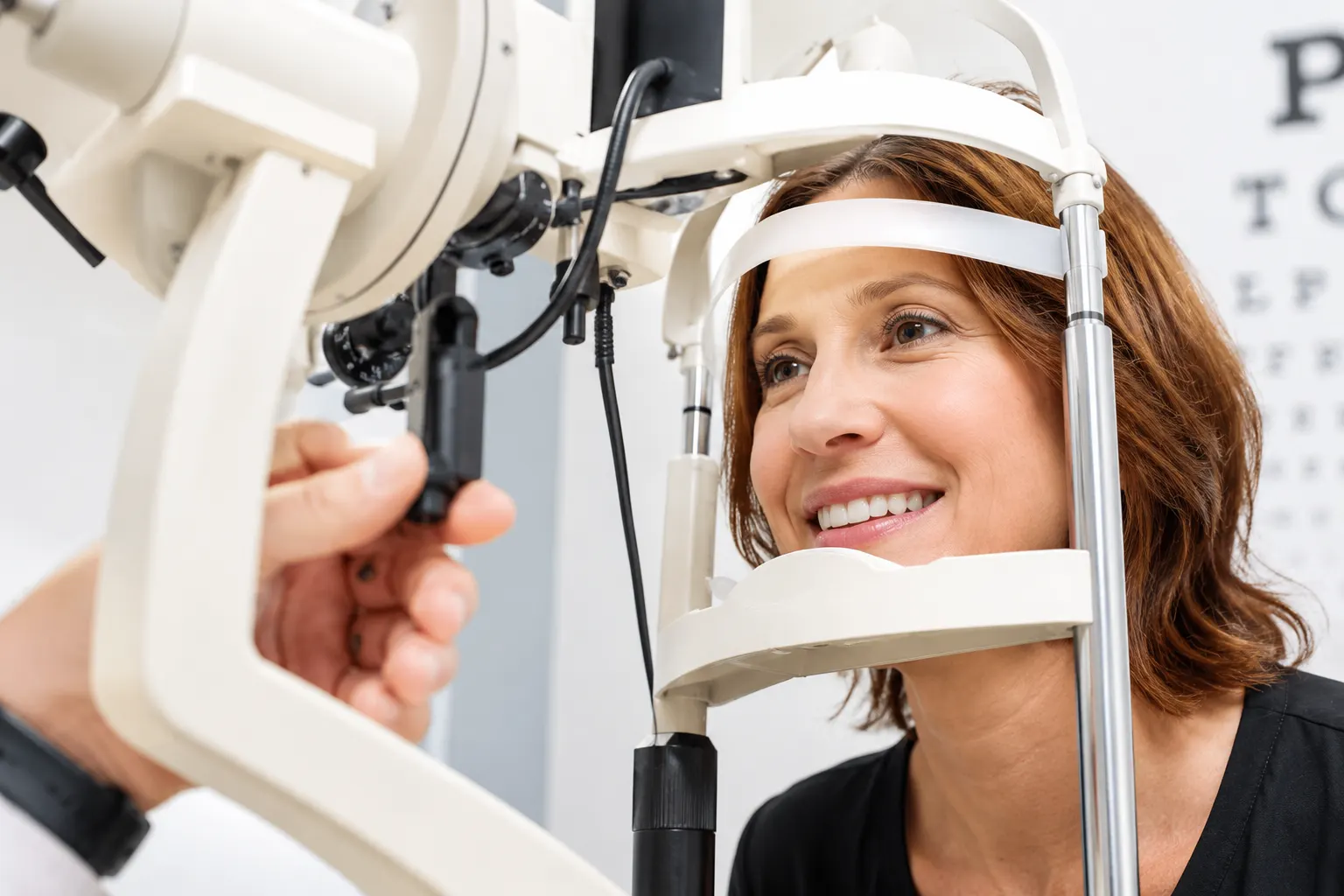 A woman sits her chin on an eye examination device.